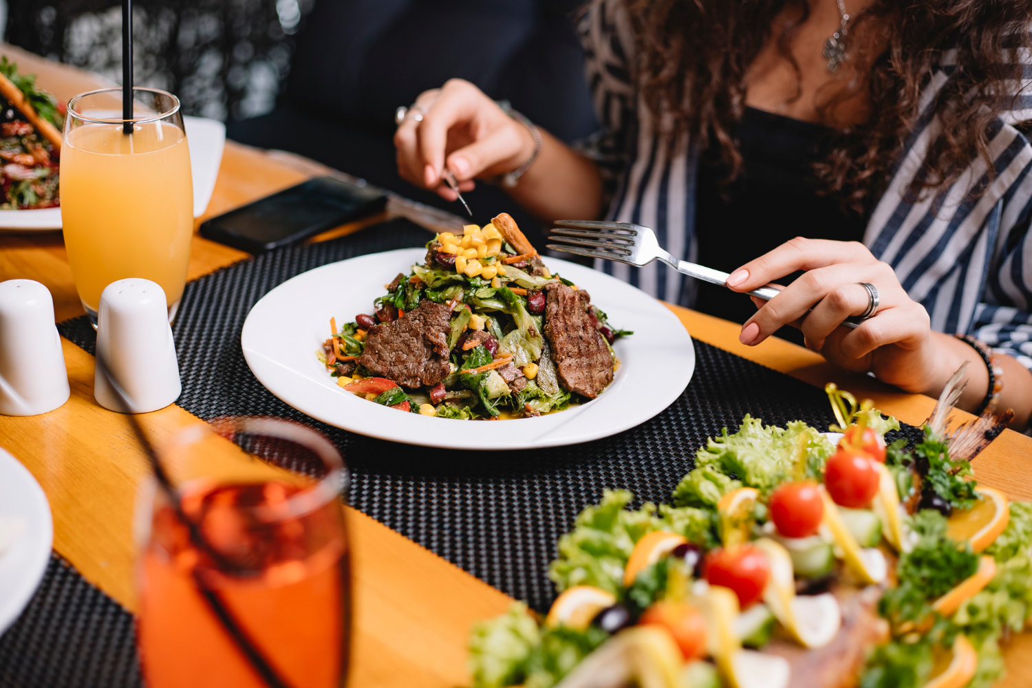 A balanced dinner plate with protein, vegetables, and carbs sits on a restaurant table, matching the idea of a more supportive evening meal.