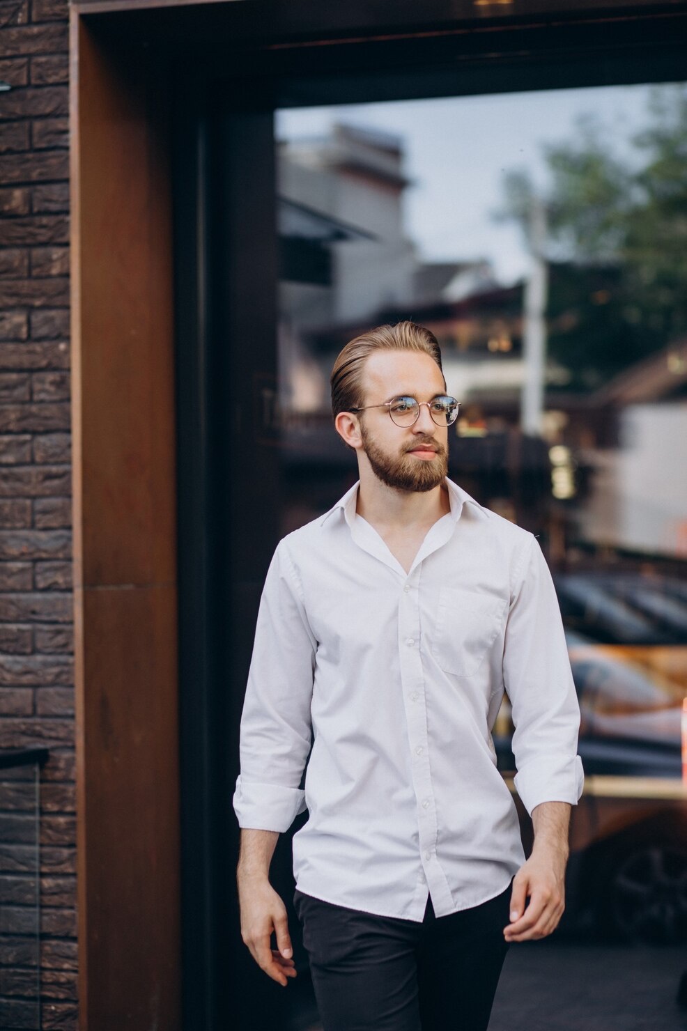 The same young professional walks through the city in his work clothes.