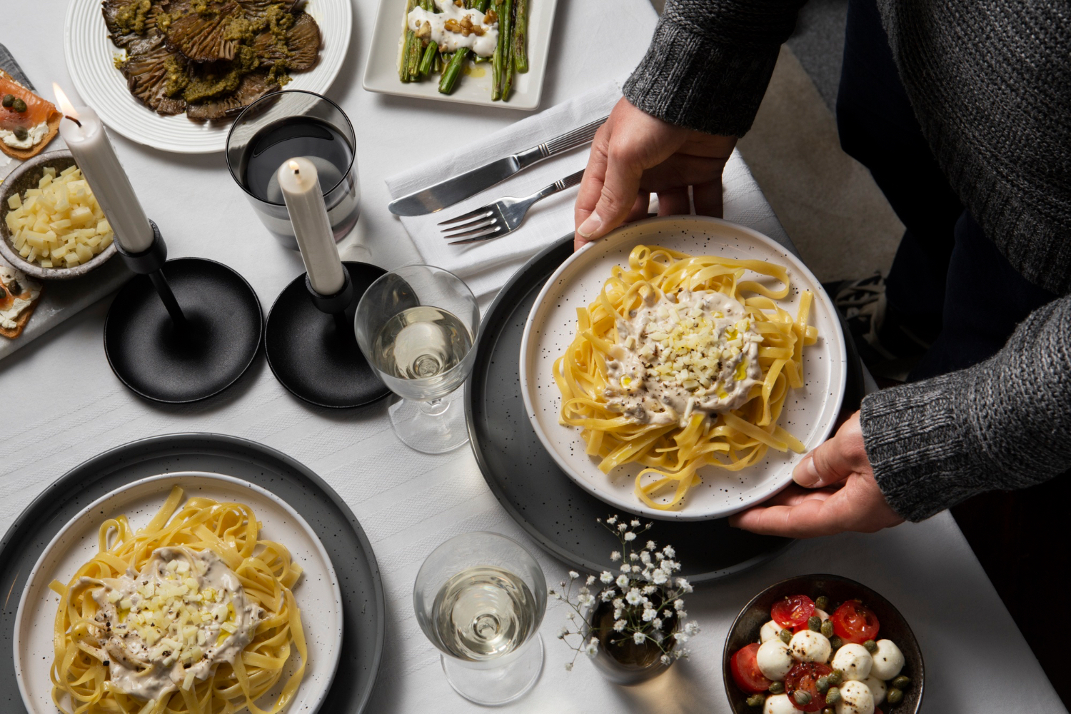 Plates of creamy pasta being set down for a late dinner.
